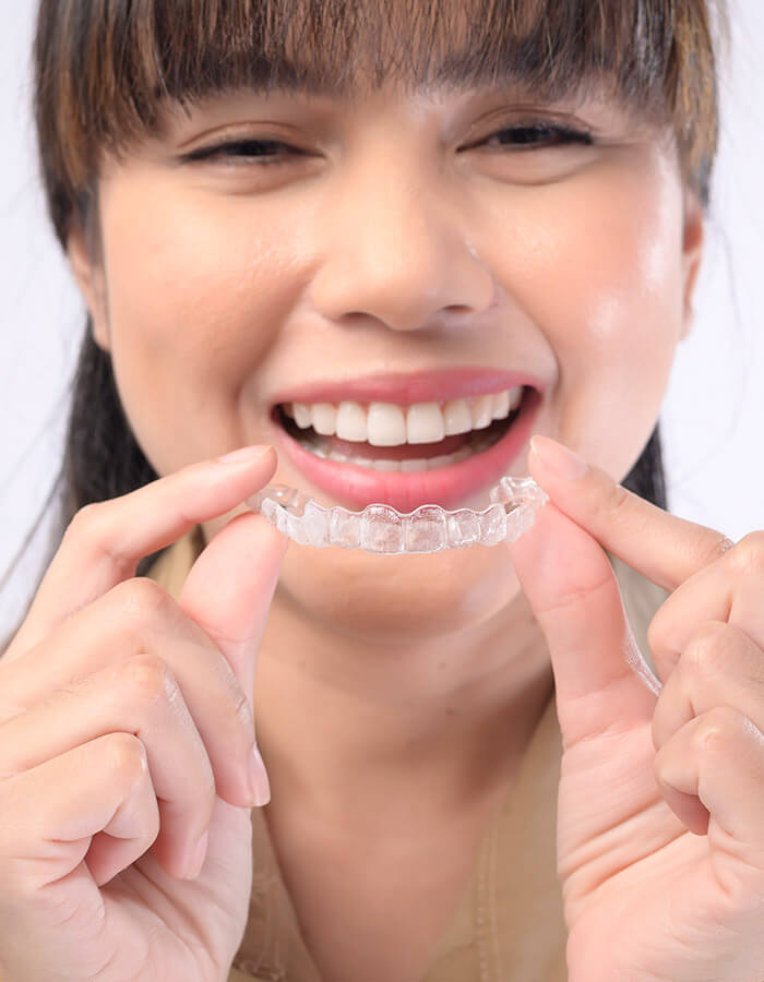 Young woman placing a clear aligner tray on her teeth